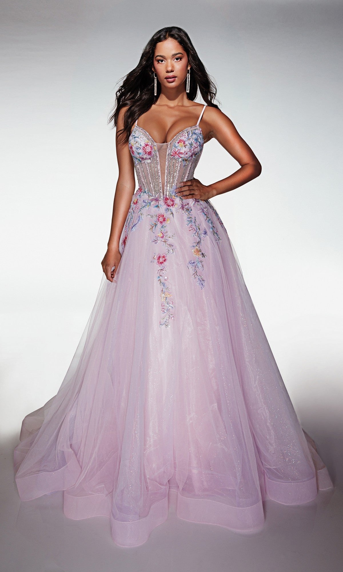 A woman wears the Long Prom Dress: Alyce 62068, a light purple sleeveless gown with a floral embroidered corset bodice, thin straps, and a full sparkling tulle A-line skirt.